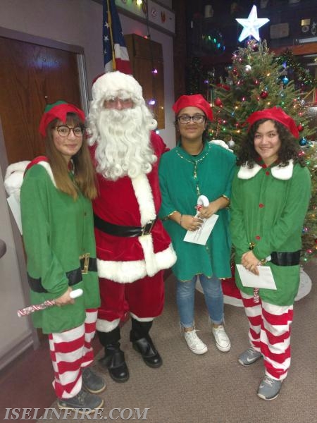 Elves Chris Gomez, Gagandeep Kaur, and Dara Mendez help Santa with presents at the Children's Christmas Party December 2017.